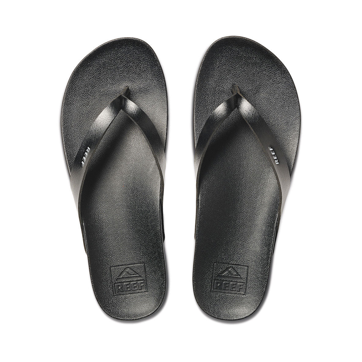 Top view of pair of black Reef Cushion Court flip-flops with logo on white background