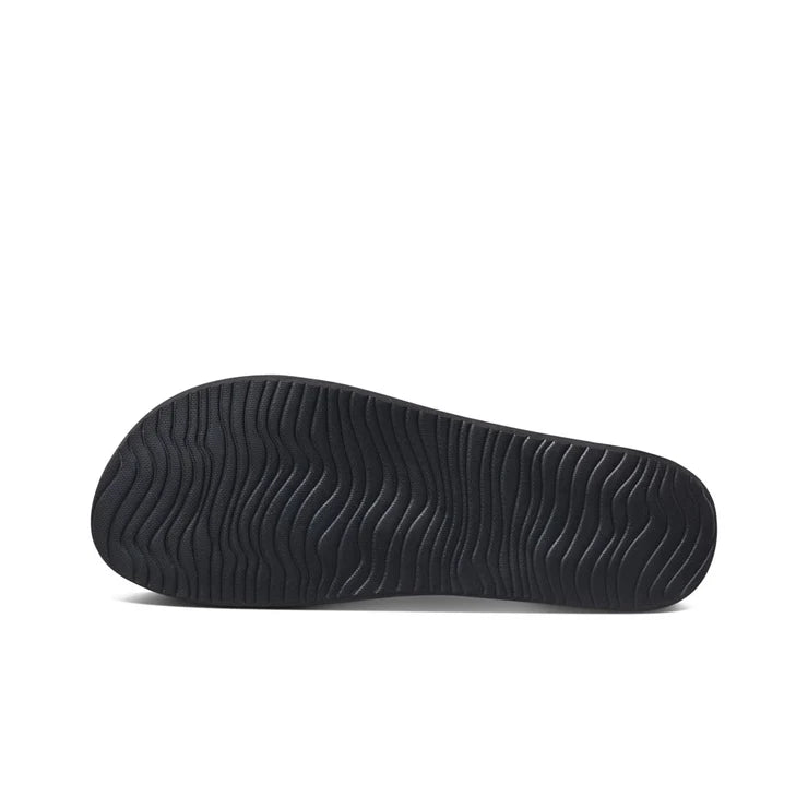 View of the black Reef Cushion Court sandal sole with wavy grip pattern on white background