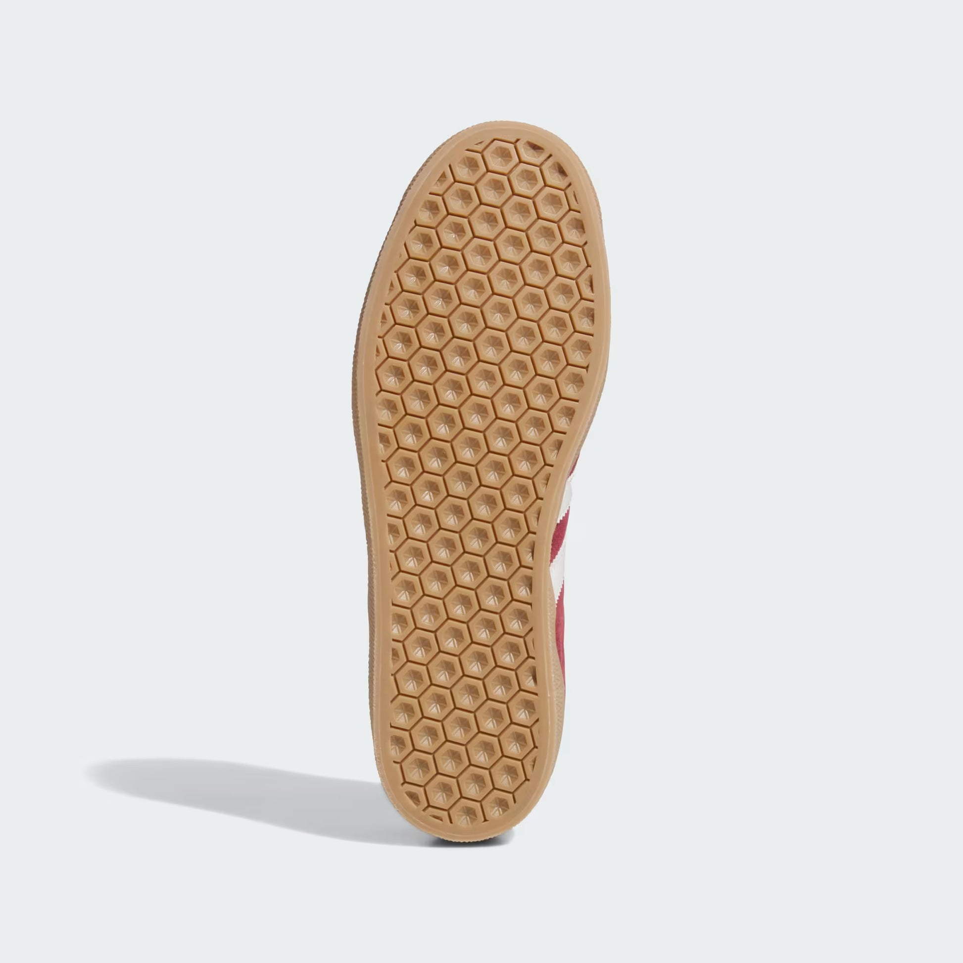 Bottom view of burgundy Adidas Gazelle ADV shoe with gum sole featuring honeycomb traction pattern on white background