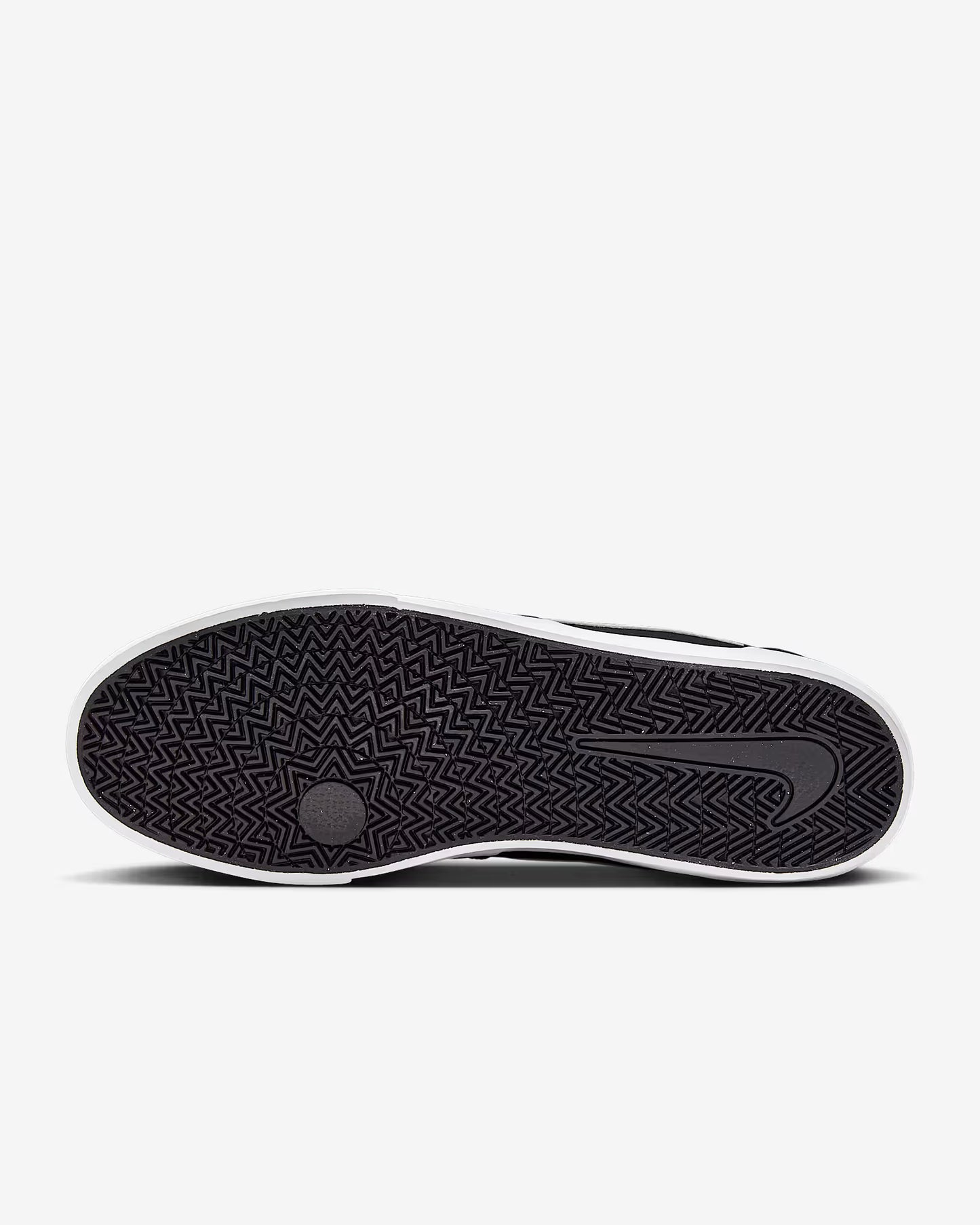 Sole view of black and white Nike SB Charge Canvas sneaker showing herringbone tread pattern on white background