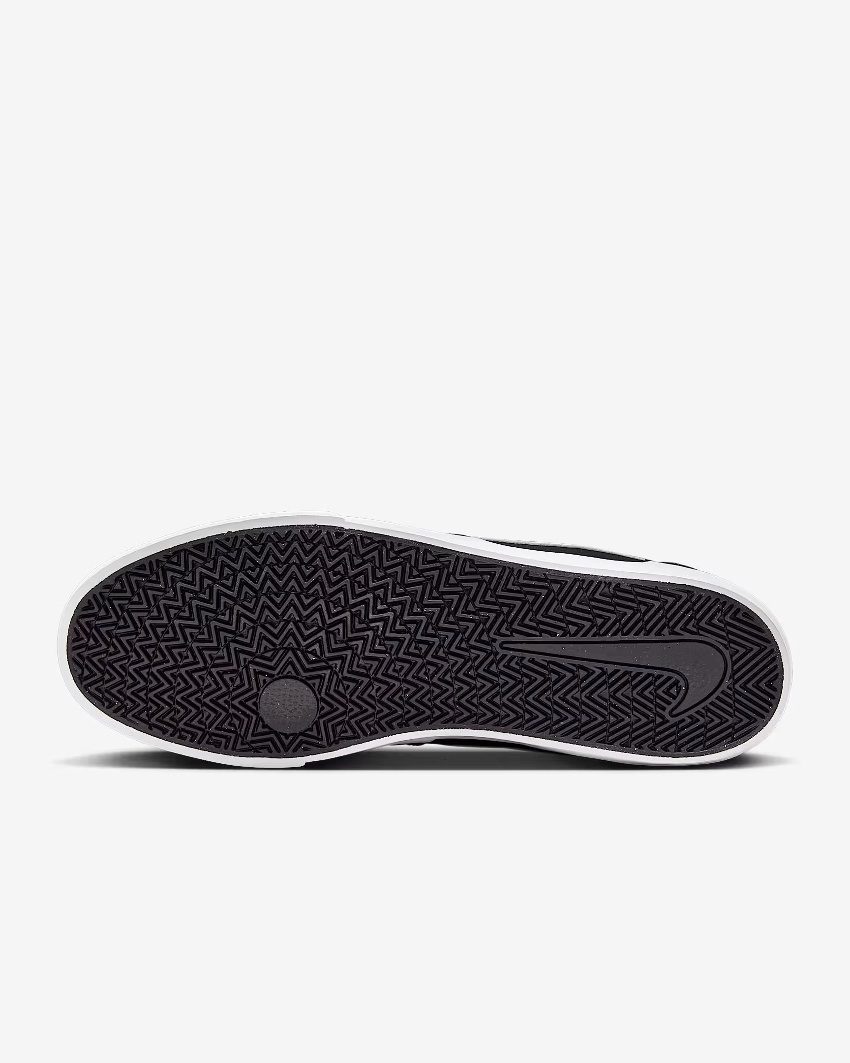 Sole view of black and white Nike SB Charge Canvas sneaker showing herringbone tread pattern on white background