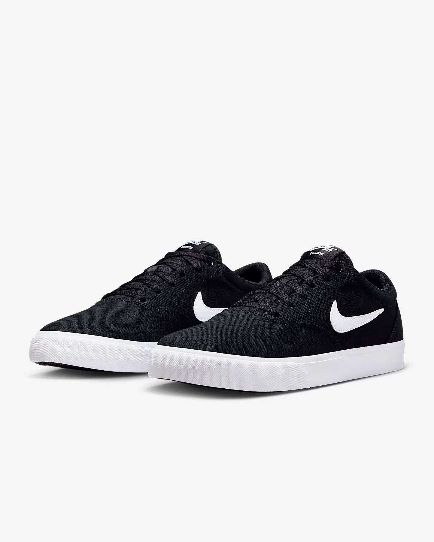 Angled side view of black Nike SB Charge Canvas sneakers with white swoosh logos and white midsoles on white background
