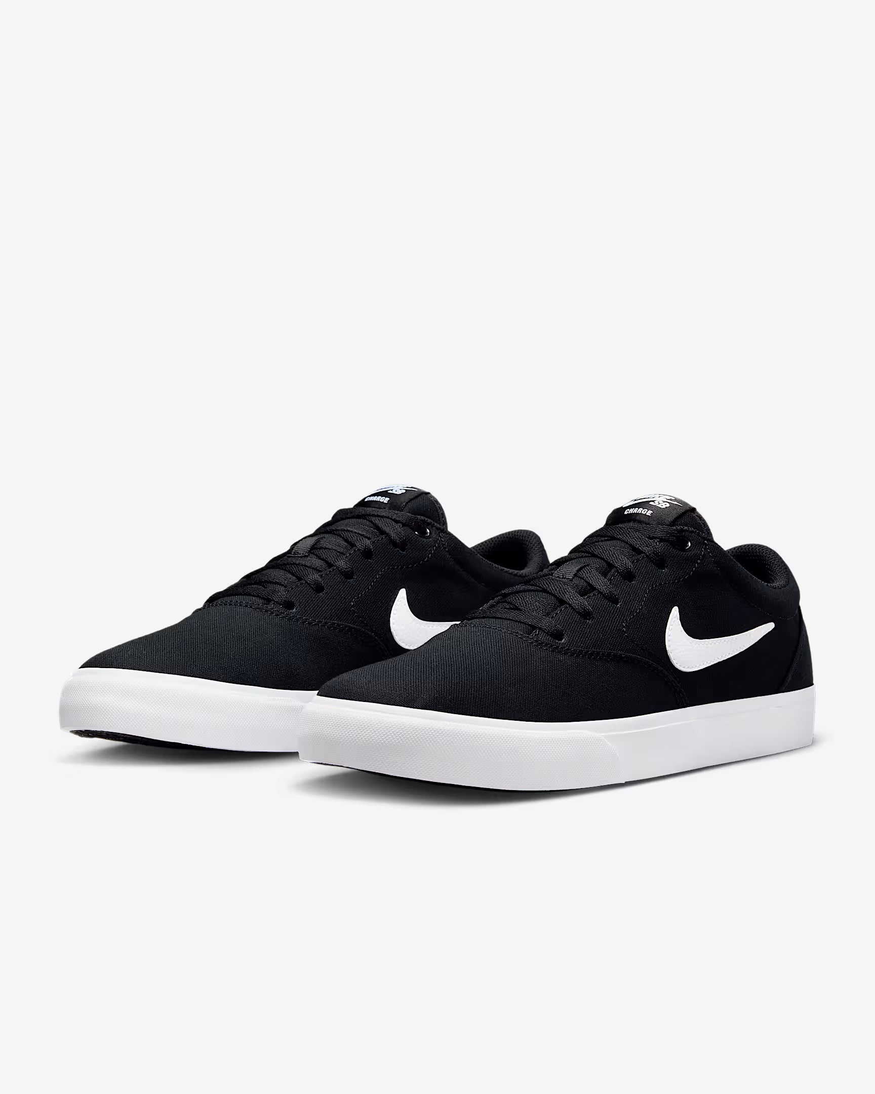 Angled side view of black Nike SB Charge Canvas sneakers with white swoosh logos and white midsoles on white background