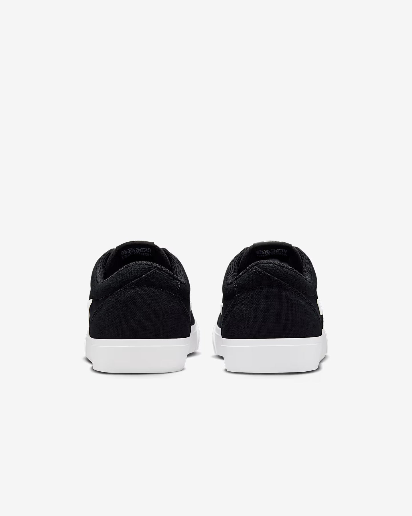 Rear view of black Nike SB Charge Canvas sneakers with white soles on white background