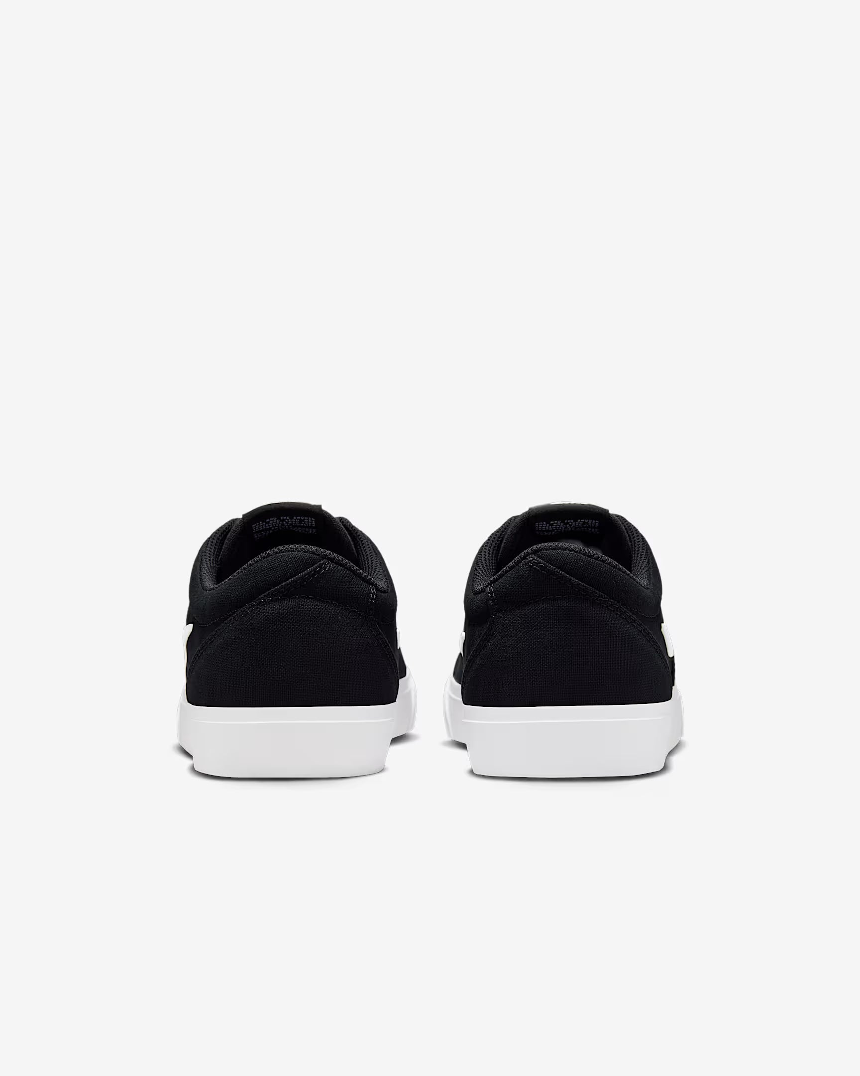 Rear view of black Nike SB Charge Canvas sneakers with white soles on white background