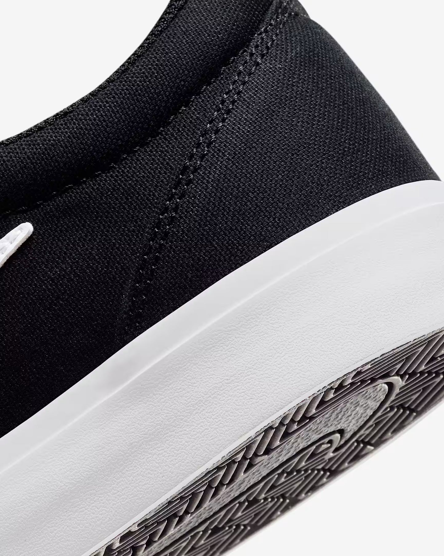 Close-up of black Nike SB Charge Canvas sneaker heel and white midsole with textured black sole pattern on white background